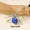 A silver crystal spider figurine with blue lapis lazuli stone resting on a wooden surface.