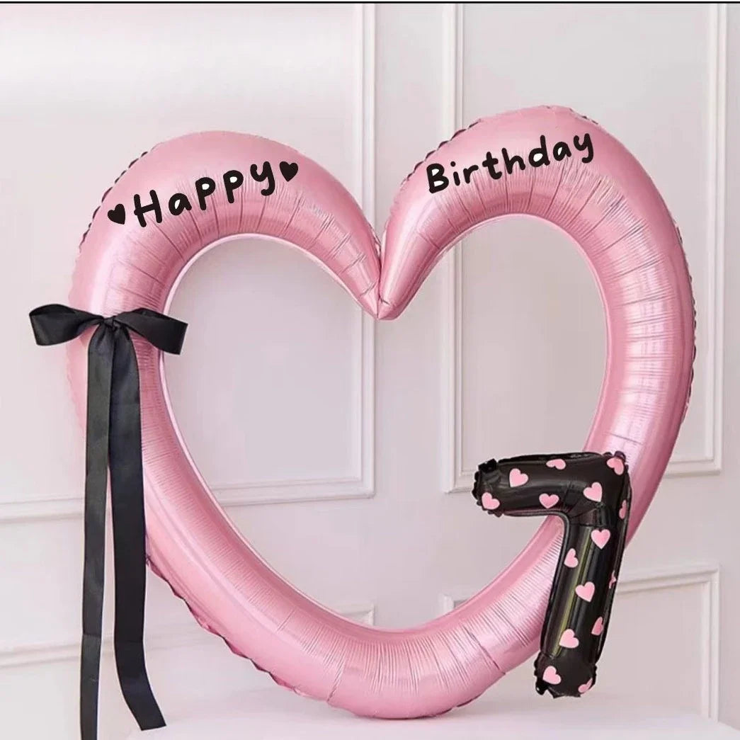 Pink heart-shaped balloon decoration with Happy and Birthday text and a black ribbon.
