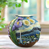 A ceramic vase decorated with a starry night landscape featuring purple and blue swirls and green foliage.