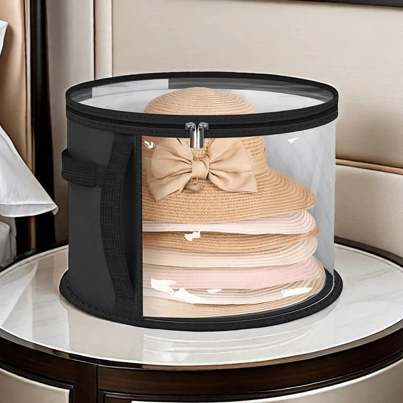 A black foldable hat storage box with a clear viewing window filled with stacked beige and pink knitted hats.