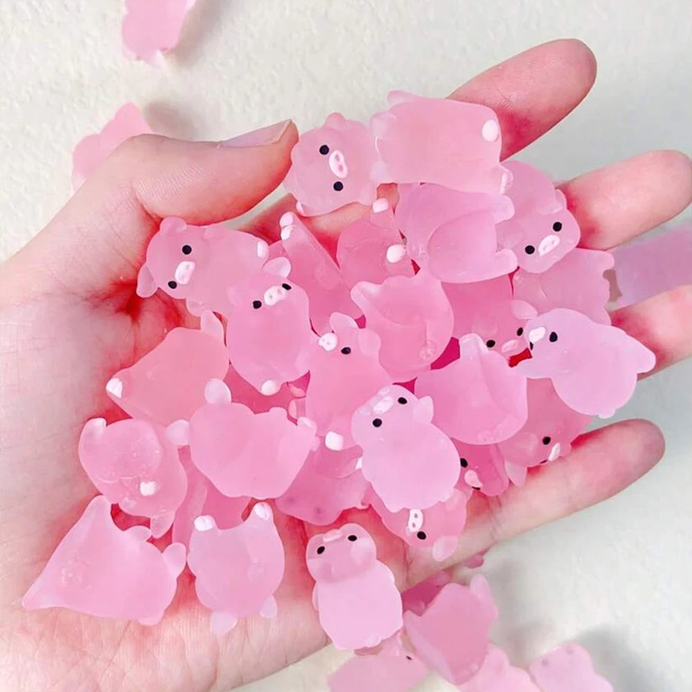A hand holds a pile of pink glow-in-the-dark resin pig decorations.