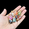 A hand holds several small glass bottles of glitter powder in various colors and textures for party decorations.