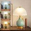 A white ceramic table lamp with a translucent shade and a pale blue glaze, shown in various light settings.