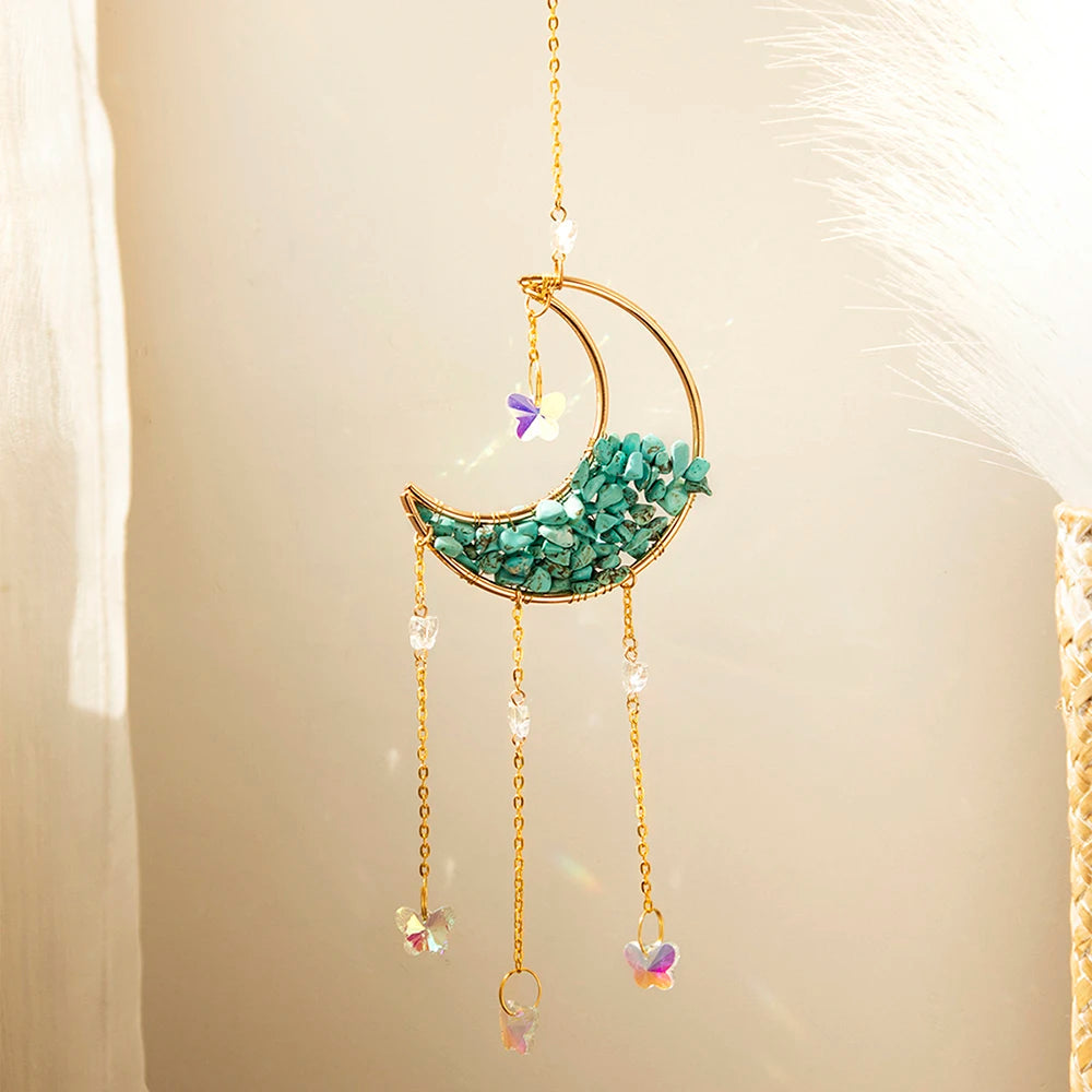 A gold dreamcatcher hangs, featuring a crescent moon made of turquoise crystals and dangling prism charms.