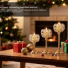 A festive scene featuring elegant metal glass candle holders, wrapped gifts, and holiday lights on a wooden table.