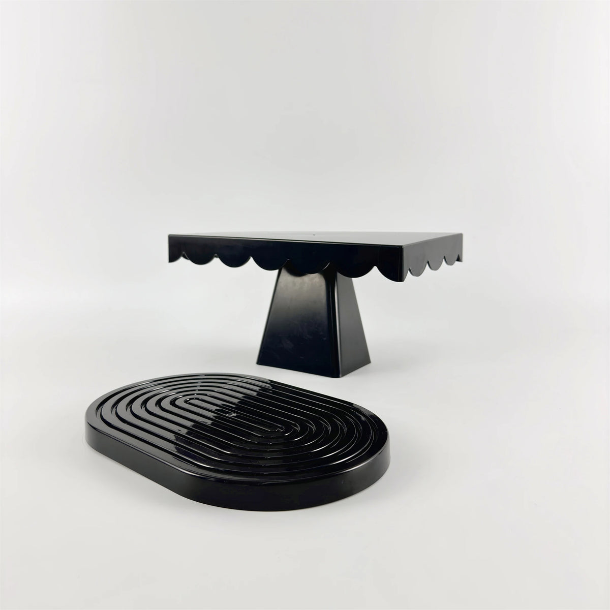 A set of two black cupcake stands with a flat top and pedestal base.