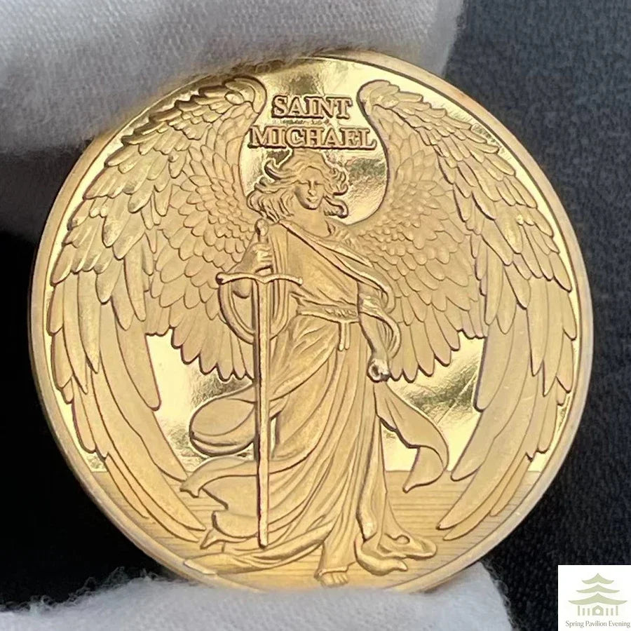 A round gold souvenir coin featuring a depiction of Saint Michael with wings and a staff.