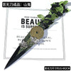 A dark decorative utility knife with a leaf-shaped blade and a gold-colored circular ornament.