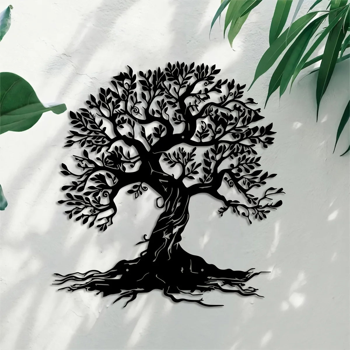 Black silhouette of a large tree with roots against a white wall, dappled sunlight visible.