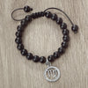 A handmade beaded bracelet with natural black stones and a silver zodiac charm