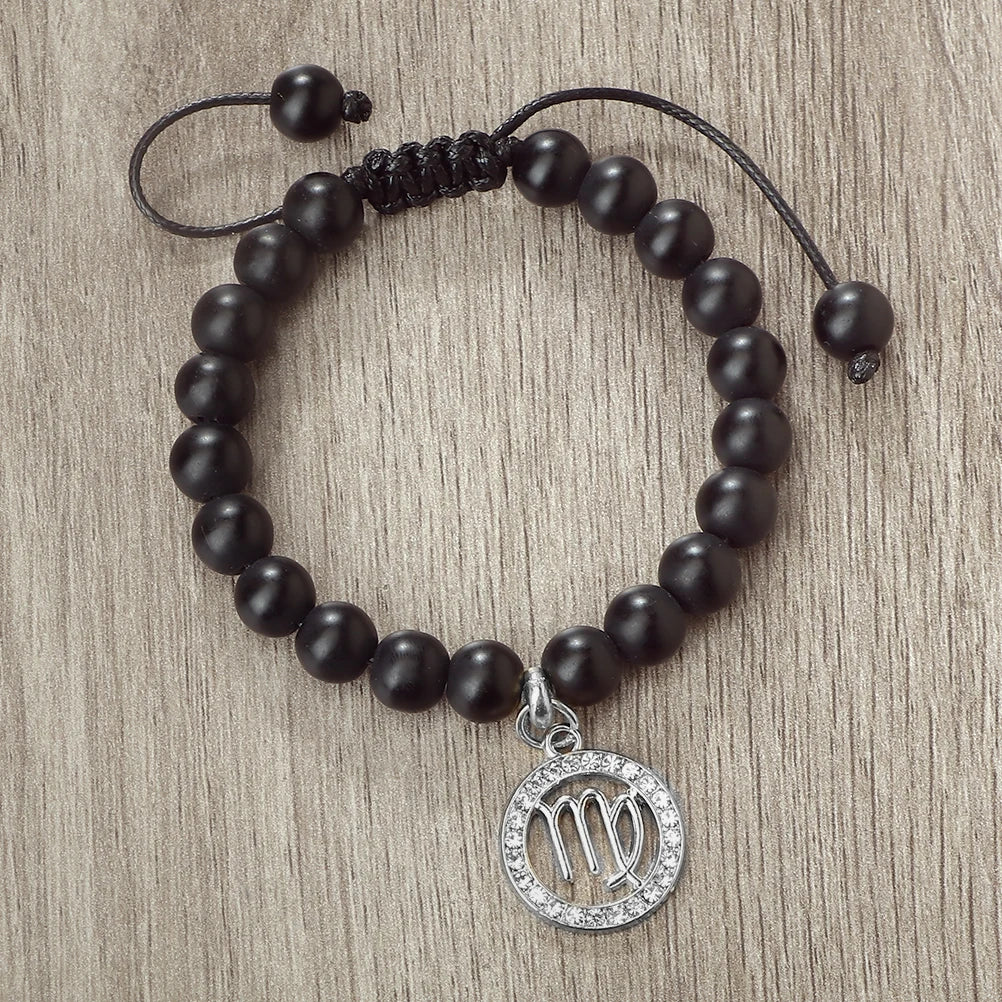 A handmade beaded bracelet with natural black stones and a silver zodiac charm