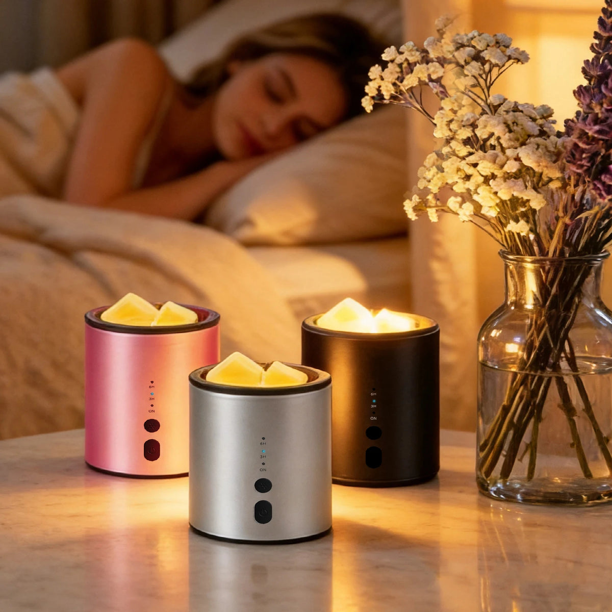Three modern ceramic candle warmer lamps with yellow wax melts sit on a wooden surface next to a bouquet of dried flowers.