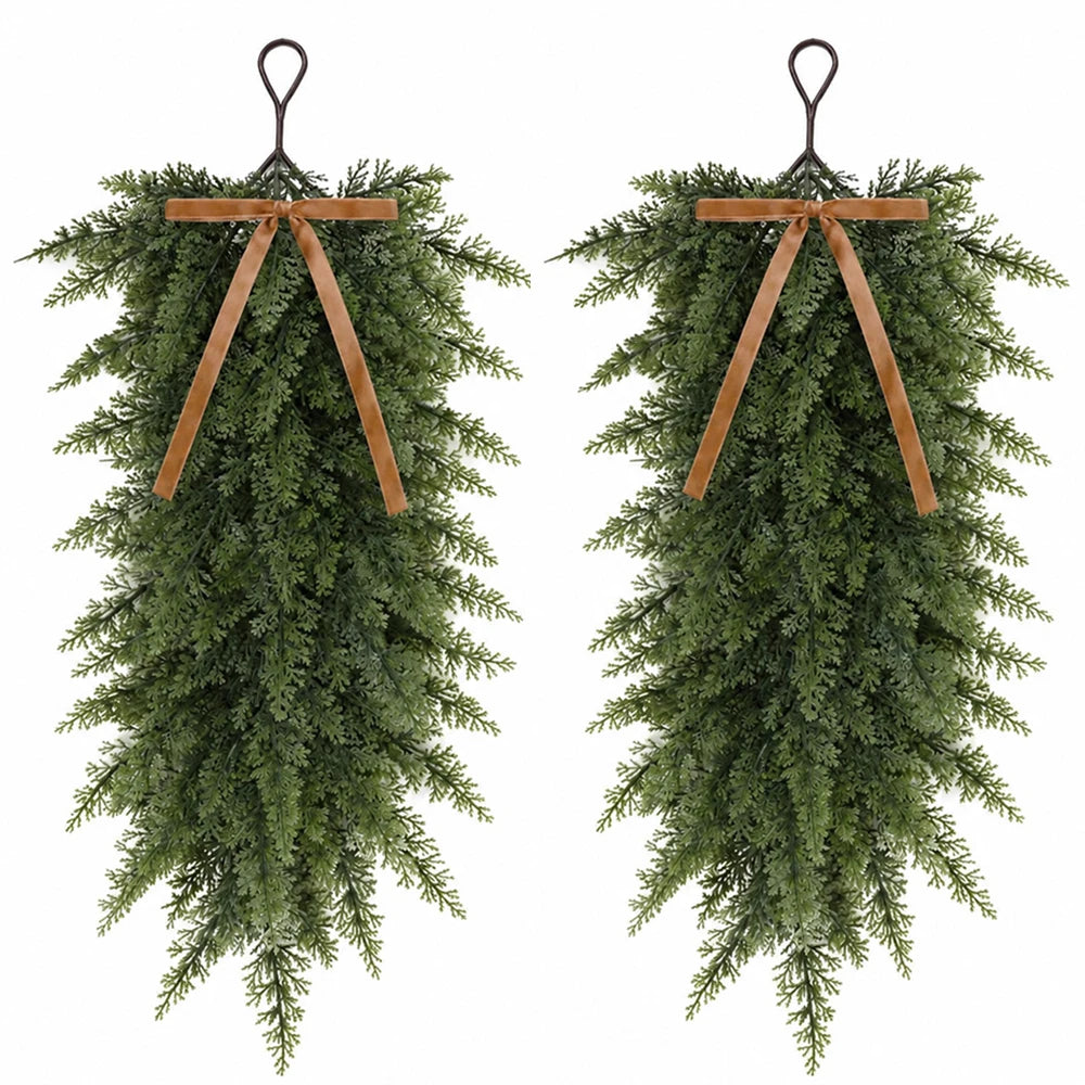 Artificial Christmas teardrop swag made of green evergreen foliage with wooden ribbon ties