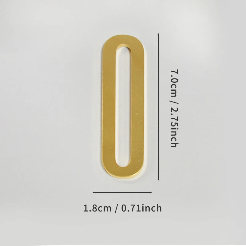 A polished gold house number shaped like the numeral zero with a self-adhesive backing.