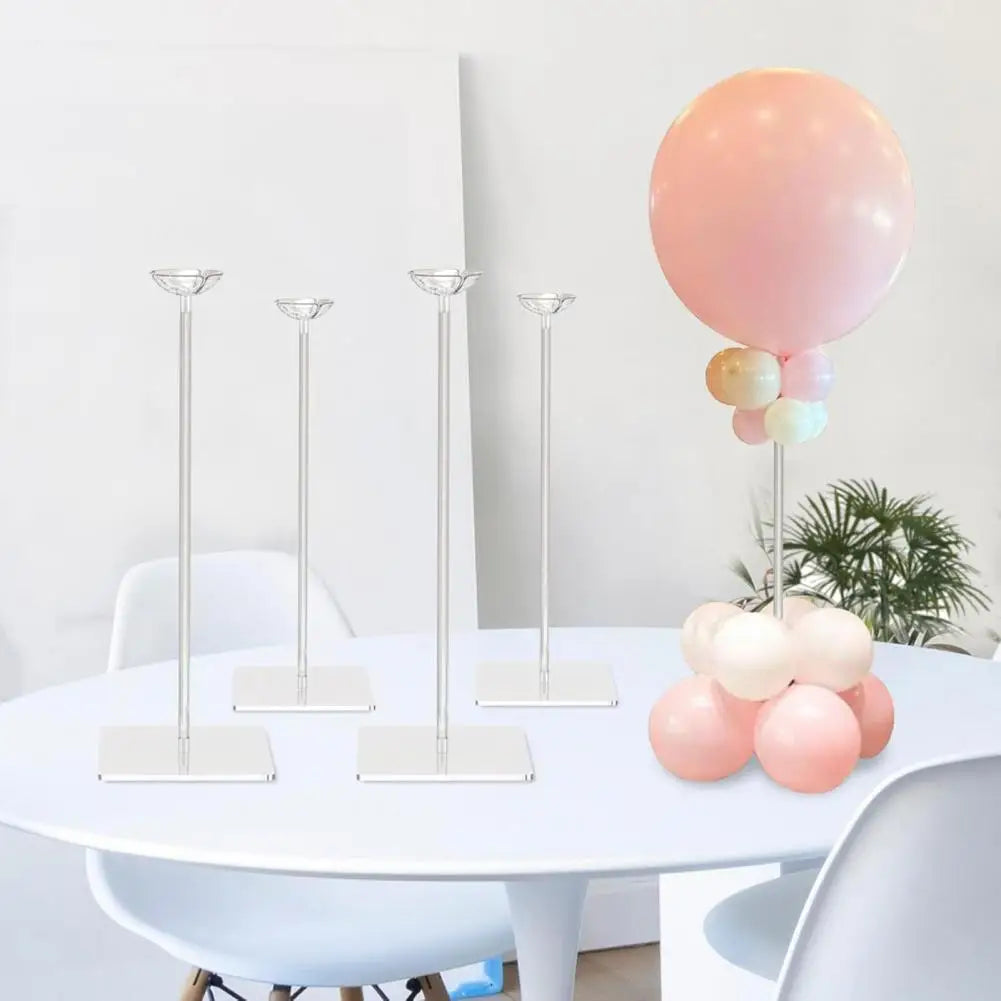 A set of clear acrylic balloon stands with pink and white balloons on a white table.