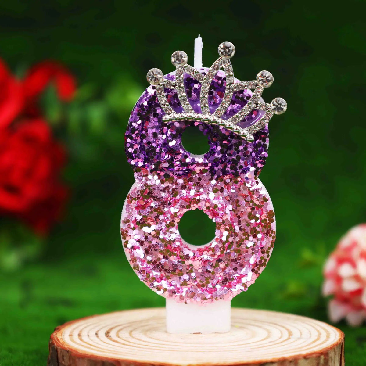 Glitter number 8 birthday candle with a rhinestone crown cake topper on a wooden surface.