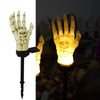 A glowing hand lantern shaped like a skull with fingers, used as a solar Halloween decoration.