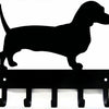 Black silhouette of a dog standing on decorative metal key hooks for wall organization
