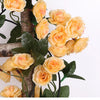 A silk rose vine garland featuring yellow and peach colored roses attached to a wooden cross branch.