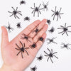 A hand holds numerous realistic mini plastic spiders for Halloween decor and pranks on a white background.