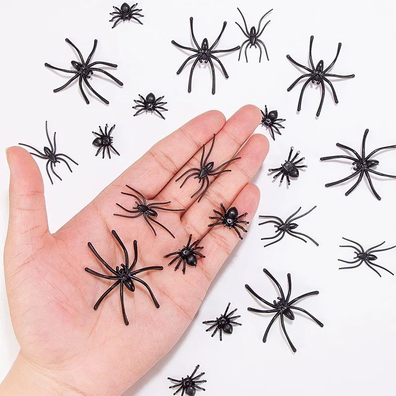 A hand holds numerous realistic mini plastic spiders for Halloween decor and pranks on a white background.