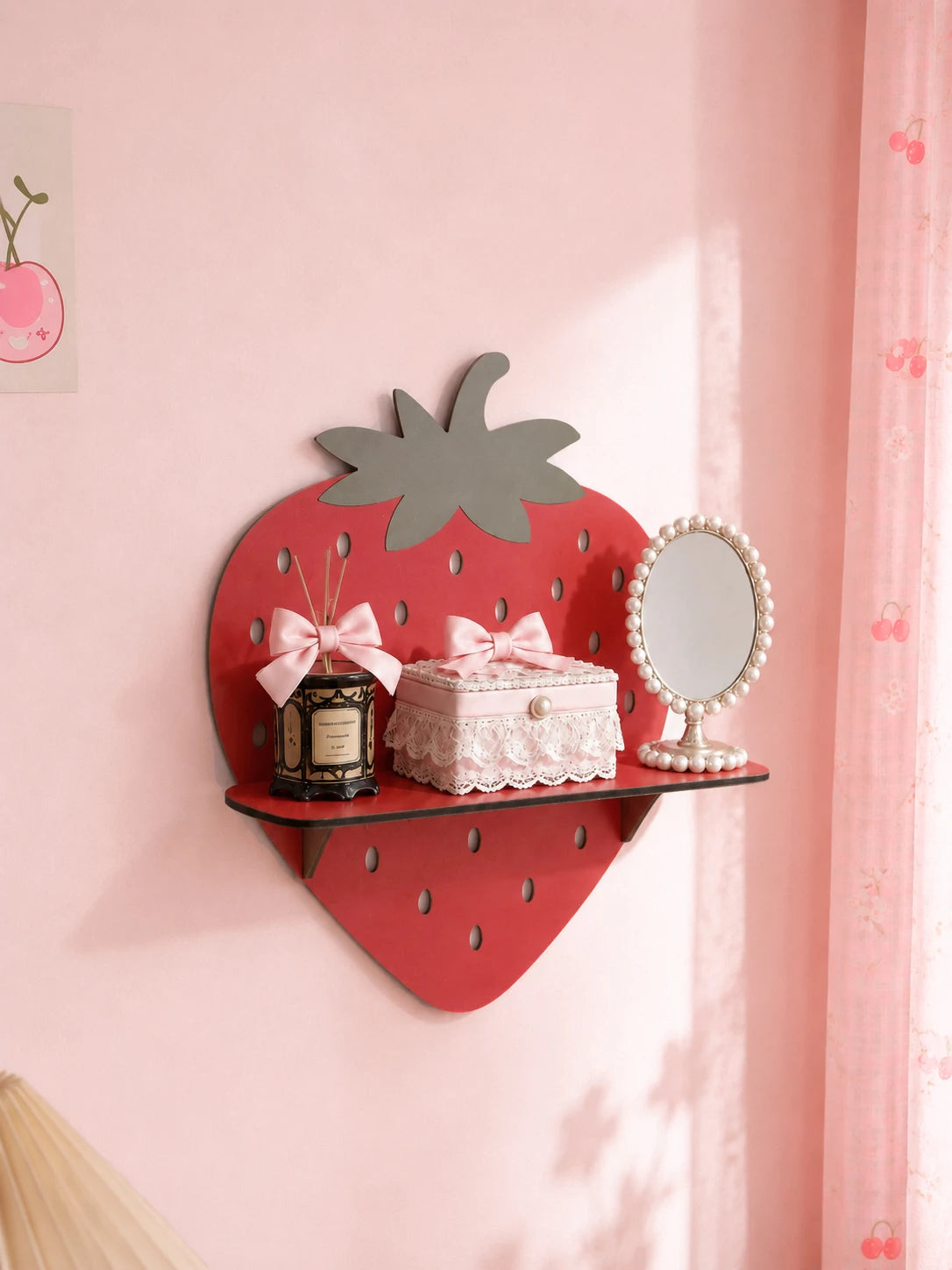 A red strawberry shaped wooden wall shelf featuring a mirror and pink floral accents on a light pink wall.
