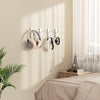 A set of four self-adhesive wall hooks for headphones displayed on a beige wall.