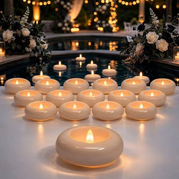 A row of white floating LED candles illuminates a dark water feature surrounded by floral arrangements.
