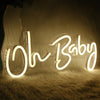A glowing neon sign spelling out Oh Baby rests on a fluffy surface.