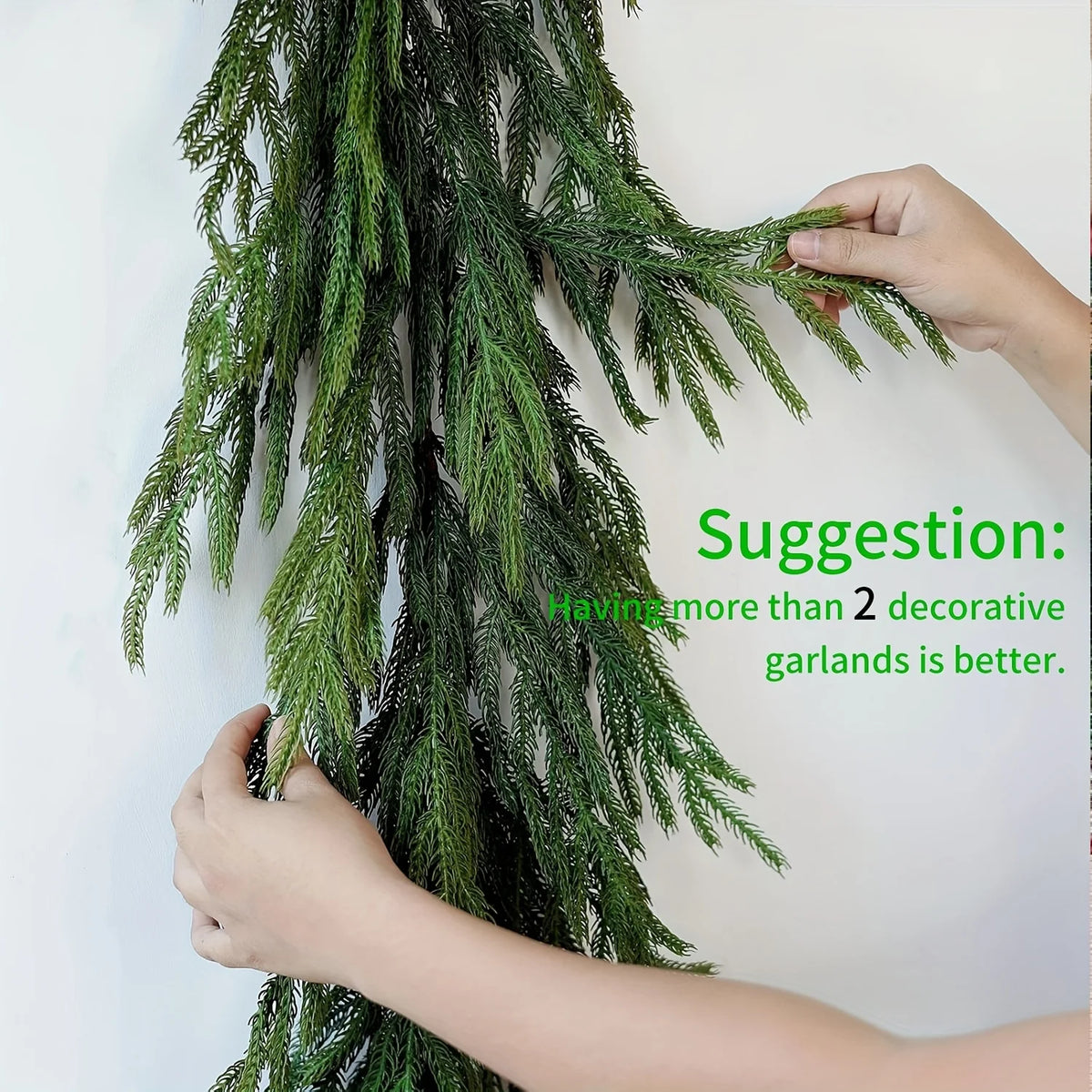 Hands are adjusting a long green artificial Norfolk pine Christmas garland.