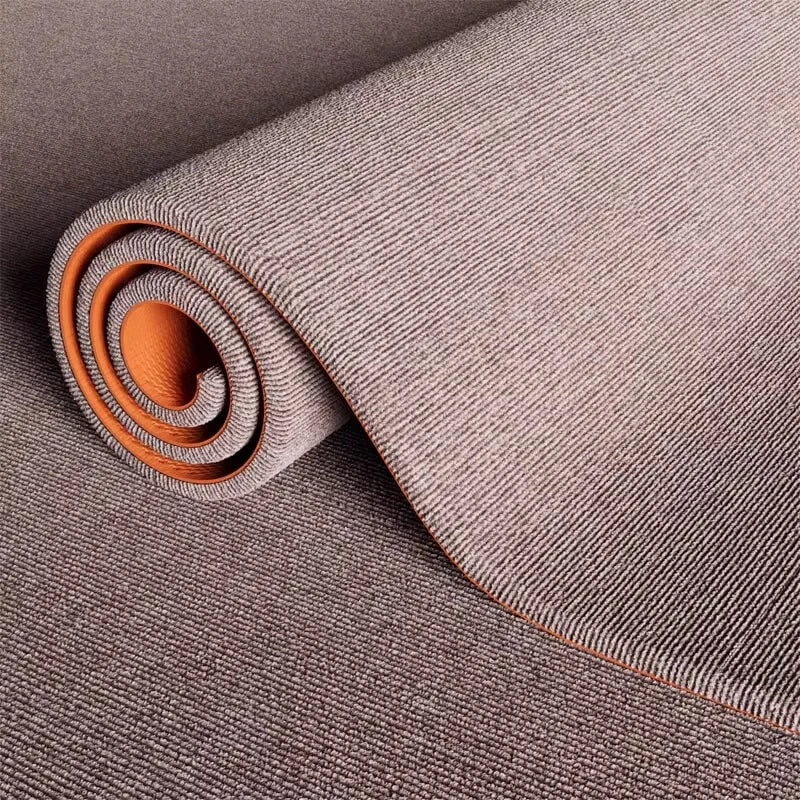 Rolled up artificial grass carpet in a neutral gray color showing its texture and weave.