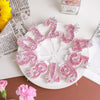 Pink sequin birthday number candles with crown toppers arranged on a white plate.