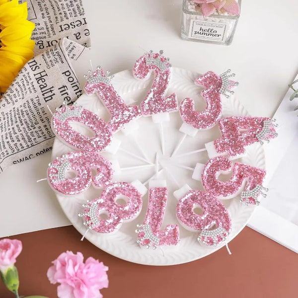 Pink sequin birthday number candles with crown toppers arranged on a white plate.