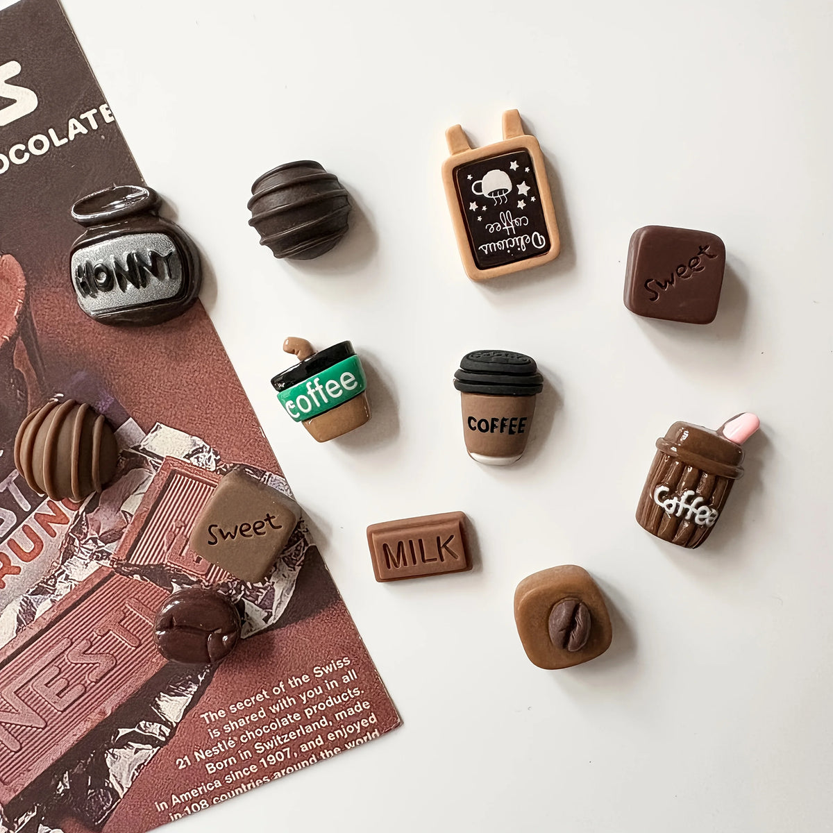 A collection of dark brown and green coffee bean fridge magnets featuring various coffee-related designs.