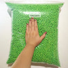 A hand is holding a clear bag filled with bright green Felicoalice foam beads for crafting.