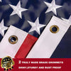 Two white embroidered American flags with brass grommets on a dark blue fabric background