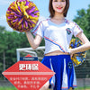 A young woman holds a vibrant purple and yellow pom pom while wearing a white athletic shirt and blue shorts.