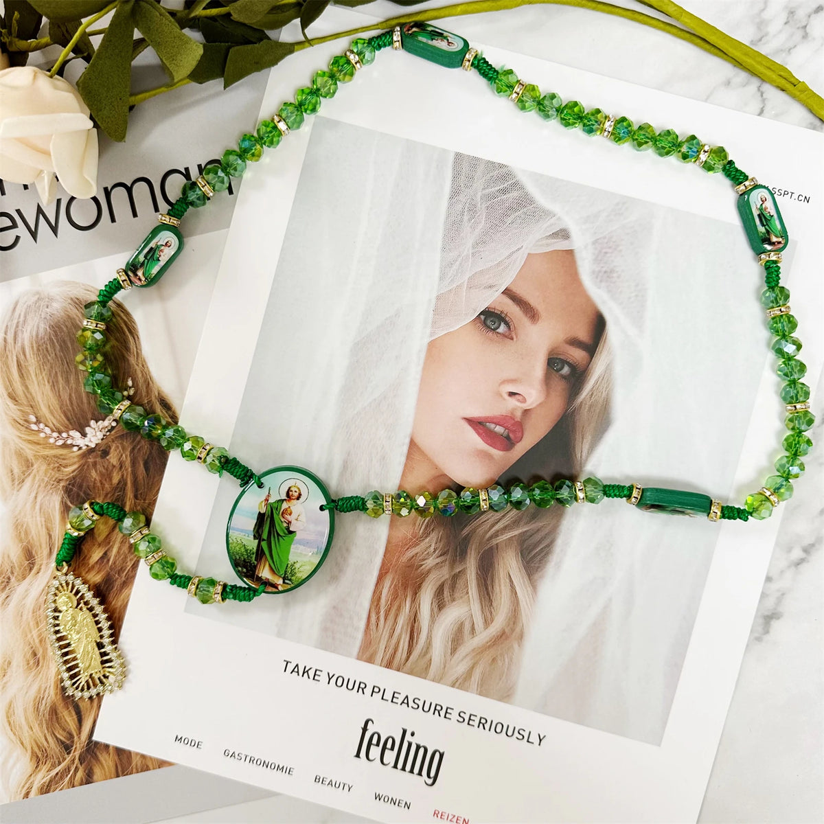 Green crystal rosary necklace featuring a Saint Jude and Virgin Mary cross pendant displayed against a soft background.