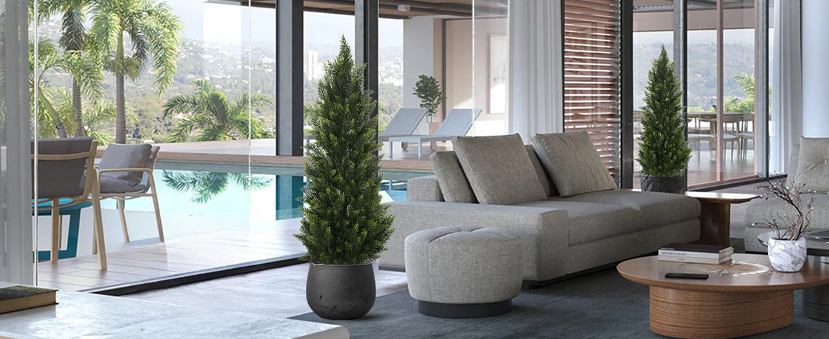 A modern living space featuring a large artificial cedar topiary tree indoors and an outdoor pool view.