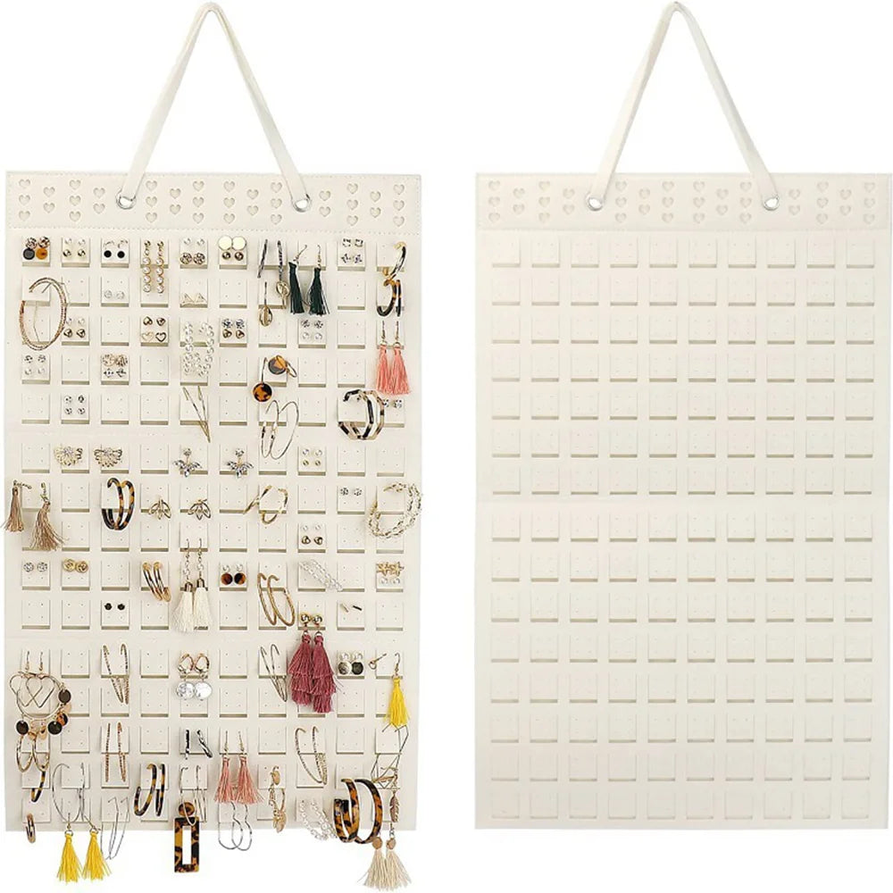 A white felt earring organizer display with numerous jewelry pieces hanging on pegs.