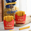 A red container of yellow french fry shaped sealing clips is displayed next to a bag of crispy fried snacks.
