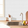 A stainless steel kitchen sink is placed on a wooden countertop in front of a white tiled backsplash.
