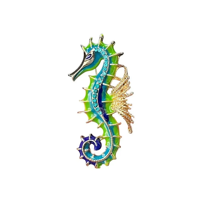 A vintage marine life brooch pin set featuring a turquoise and green dragon-like creature with gold accents.