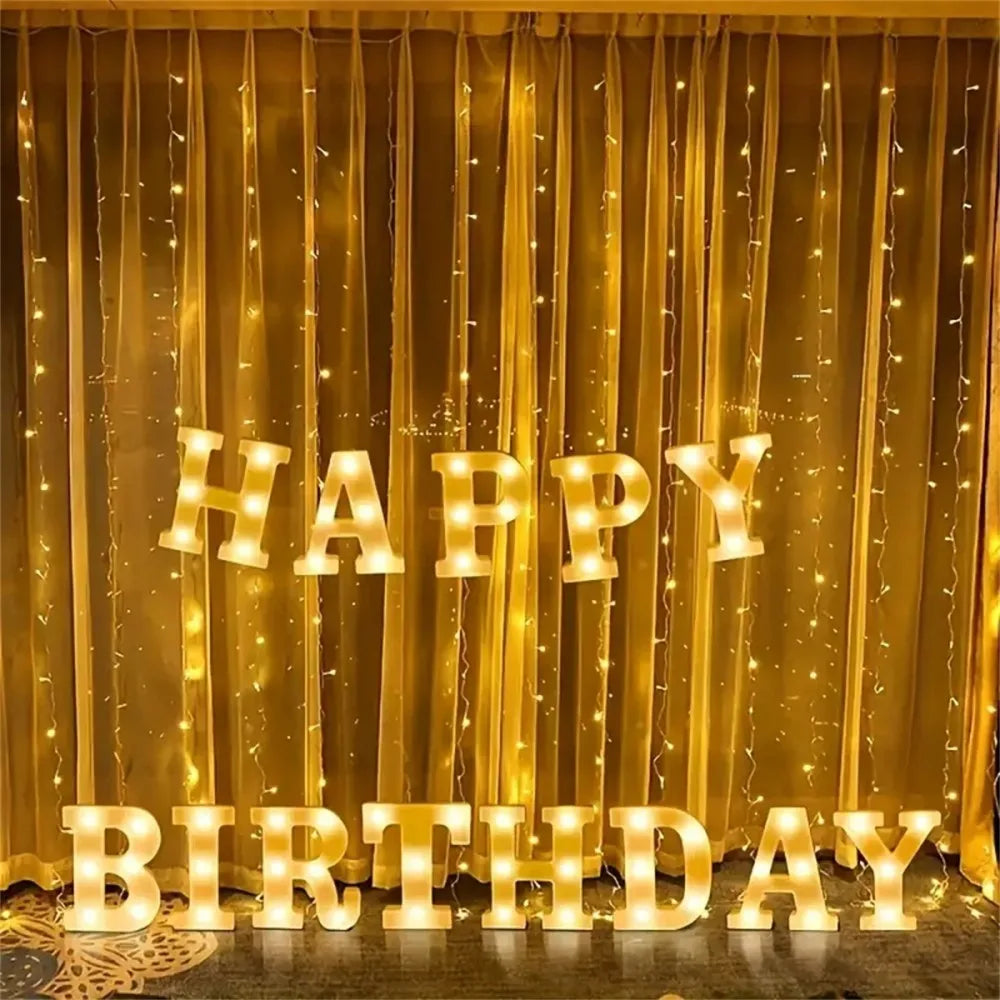 Golden curtain decorated with warm LED letter lights spelling HAPPY BIRTHDAY
