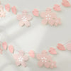 Pink paper cherry blossom flower banner strung across a white background