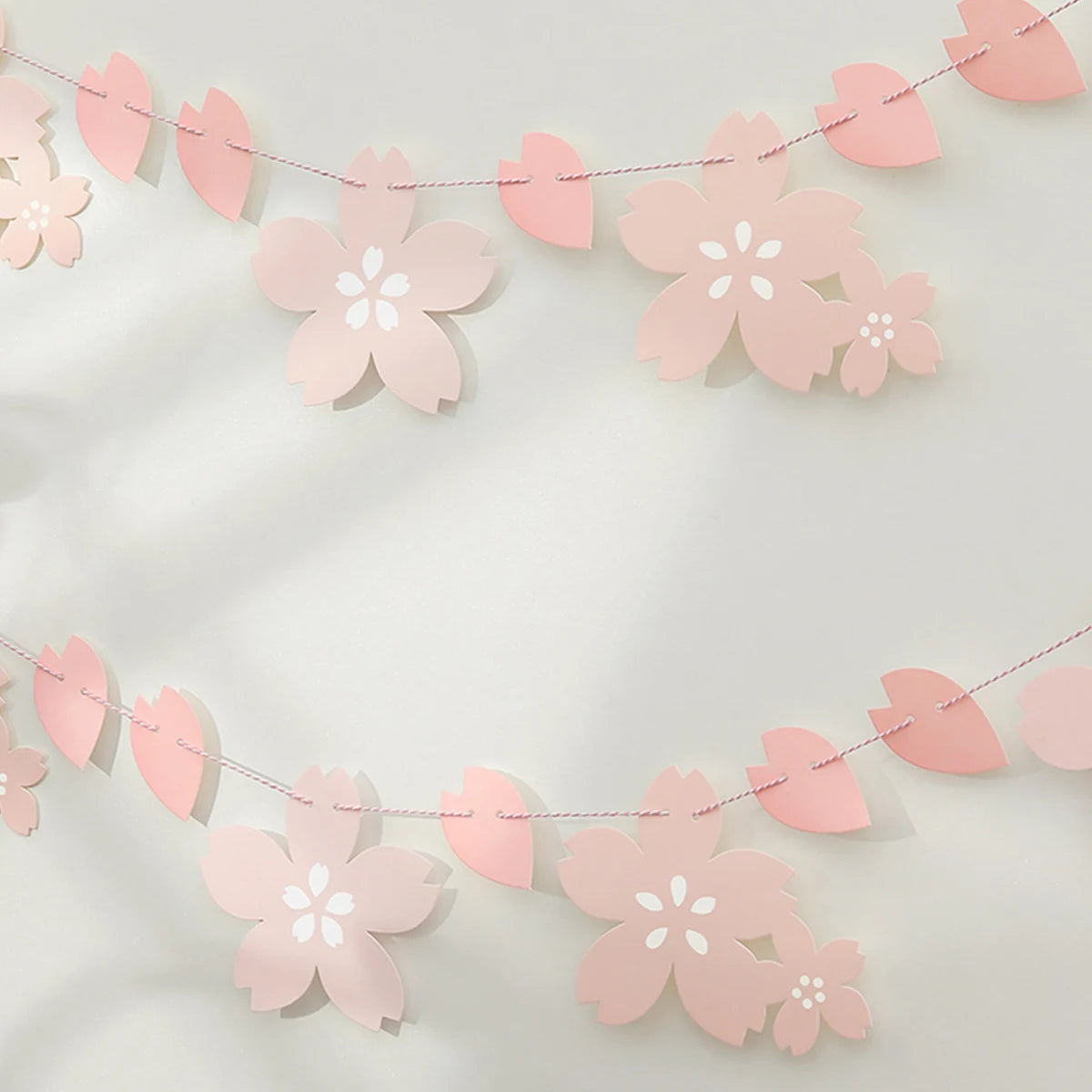 Pink paper cherry blossom flower banner strung across a white background