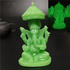A bright green statue of Ganesha Buddha seated in a meditative pose on a round base.