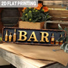 A vintage metal sign spelling out BAR, featuring a rustic, aged finish, displayed on a wooden surface.