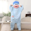 A light blue coral fleece hooded sleepsuit resembling a monster with pink features is displayed on a couch.