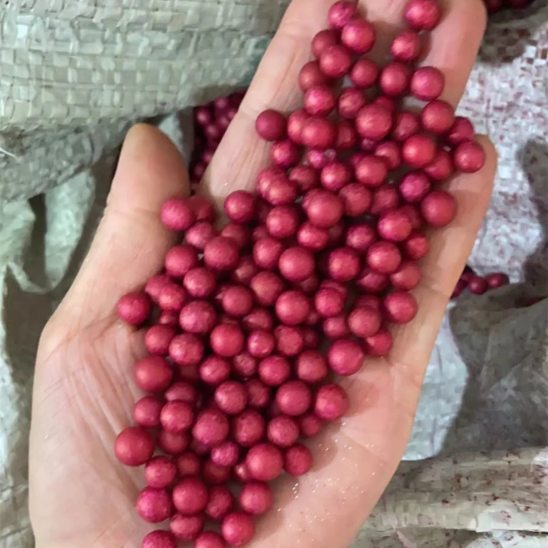 A hand holds a large quantity of deep pink foam beads for crafting and decoration.
